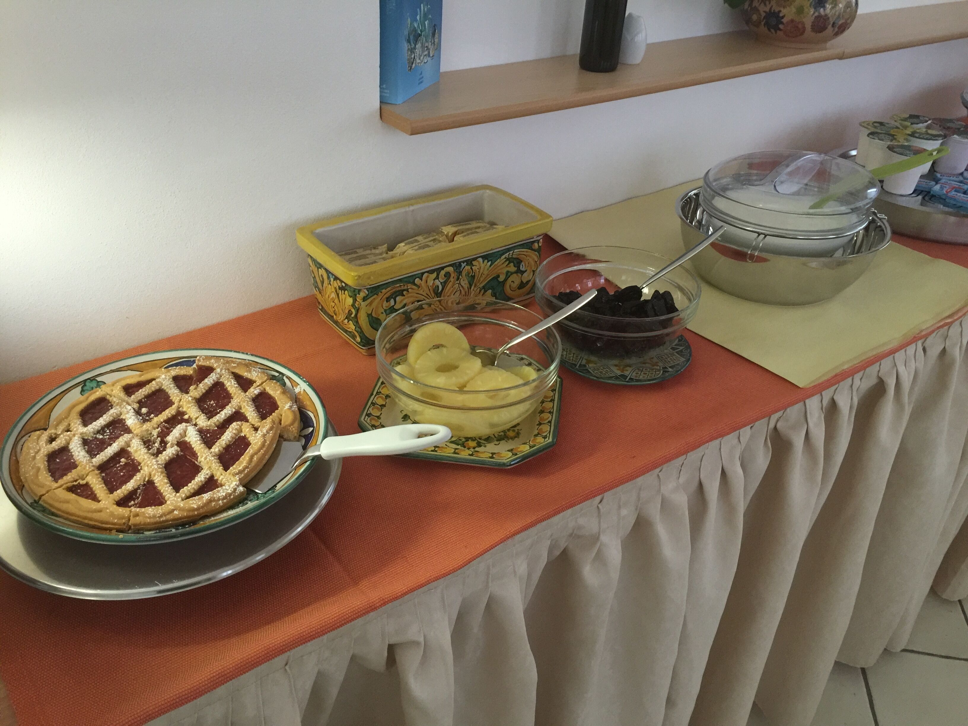 A buffet table with a pie, a bowl of mashed potatoes, and a container of blackberries.