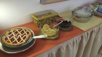 A buffet table with a pie, a bowl of mashed potatoes, and a container of blackberries.