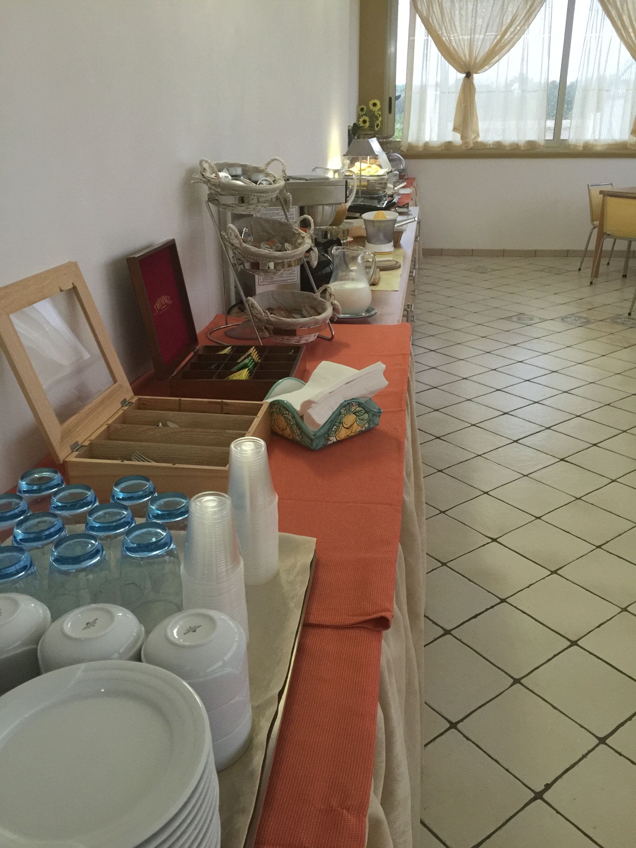 A room with a long table set up with various items including plates, cups, and baskets.
