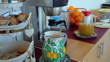 Una encimera de cocina con una cafetera, un exprimidor de frutas y diversos utensilios de cocina.