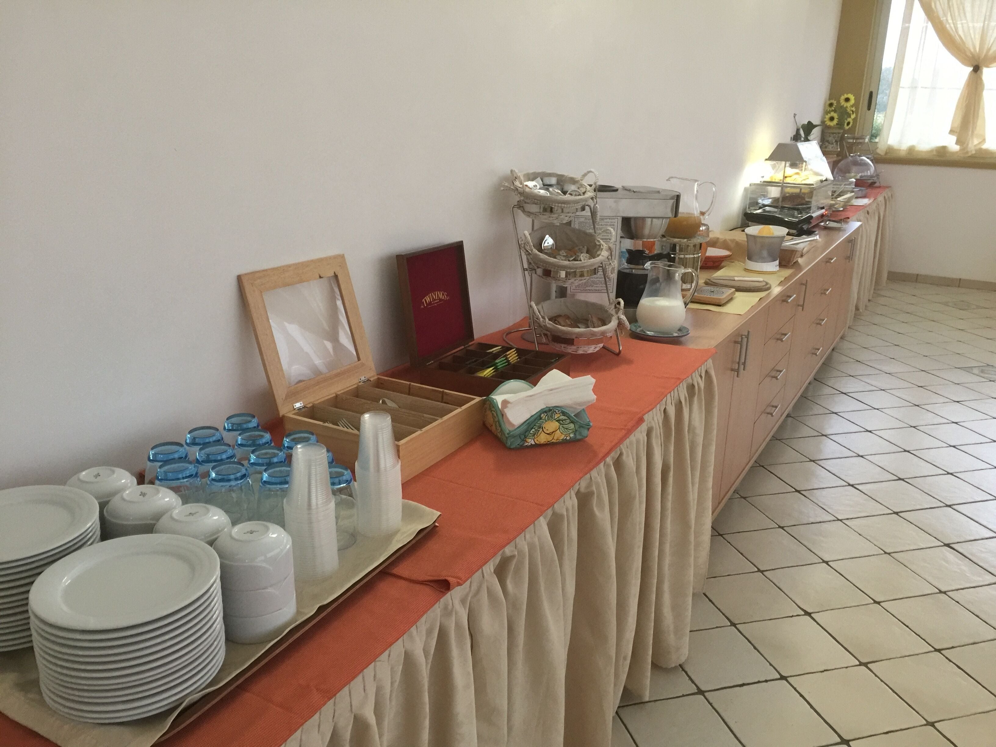 A buffet setup with plates, bowls, and a milk jug on a table.
