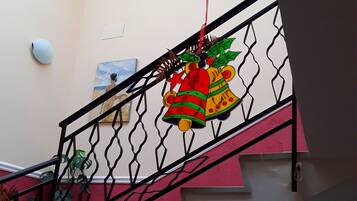 A staircase with a railing, a painting on the wall, and a hanging decoration.