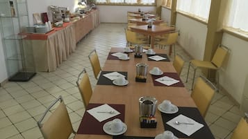 A dining area with multiple tables set for breakfast, including plates, cups, and cutlery.