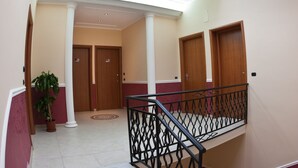 A spacious interior with a curved staircase, a ceiling with a grid pattern, and a potted plant. - B&B Il Tempio di Hera (Castelvetrano)