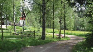 A rural road leading to a red building with a white facade, surrounded by lush greenery and trees. - 2 bedroom amazing home in Hestra (Hestra)