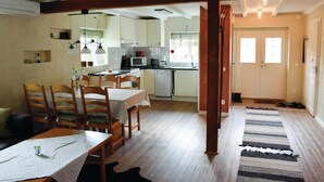 A cozy kitchen with wooden cabinets, a dining area with a table and chairs, and a view of the outside through a door. - 2 bedroom amazing home in Hestra (Hestra)
