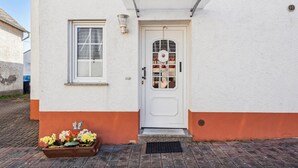 A white building with a white door, a small window, and a flower box with flowers. - Cozy home in Strohn with kitchen (Strohn)