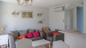 A living room with a sofa set, a coffee table, and a dining table. There is a chandelier, wall-mounted lamps, and a painting on the wall. - Awesome home in Montauroux (Montauroux)