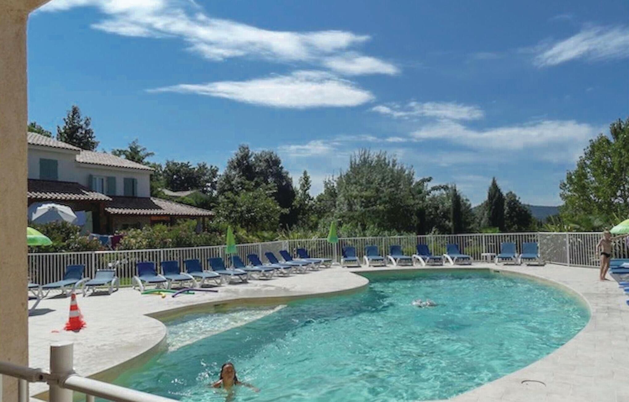Una piscina amb gandules i una vista d'una casa al fons.