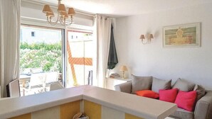 A living room with a sofa, a small table, and a kitchen area with a counter. - Awesome home in Montauroux (Montauroux)