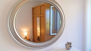 Een ronde spiegel met een houten deur en een lamp in het spiegelbeeld.