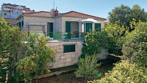 Een stenen gebouw met een balkon, groene luiken en een schotelantenne.