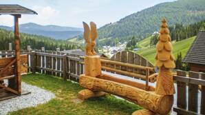 Un banc en bois orné de sculptures et une clôture en bois, le tout situé dans une région montagneuse.