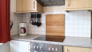A kitchen with wooden cabinets, a stainless steel stove, a coffee maker, and a knife rack. - 1 bedroom nice apartment in Börgerende (Börgerende)