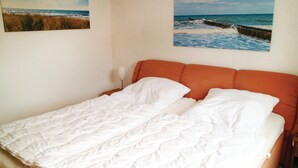 A bed with white bedding in a room with two beach-themed wall art pieces. - 1 bedroom nice apartment in Börgerende (Börgerende)