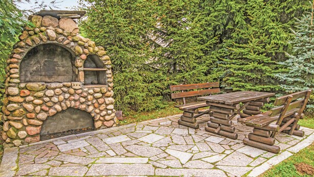 A stone-built outdoor kitchen with a pizza oven, wooden benches, and a picnic table. - 3 bedroom cozy home in Dabrówno (Dabrówno)