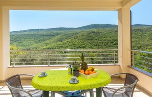A balcony with a table set for two, a pineapple, a bowl of oranges, and a potted plant. - Lovely apartment in Labin with WiFi (Labin)