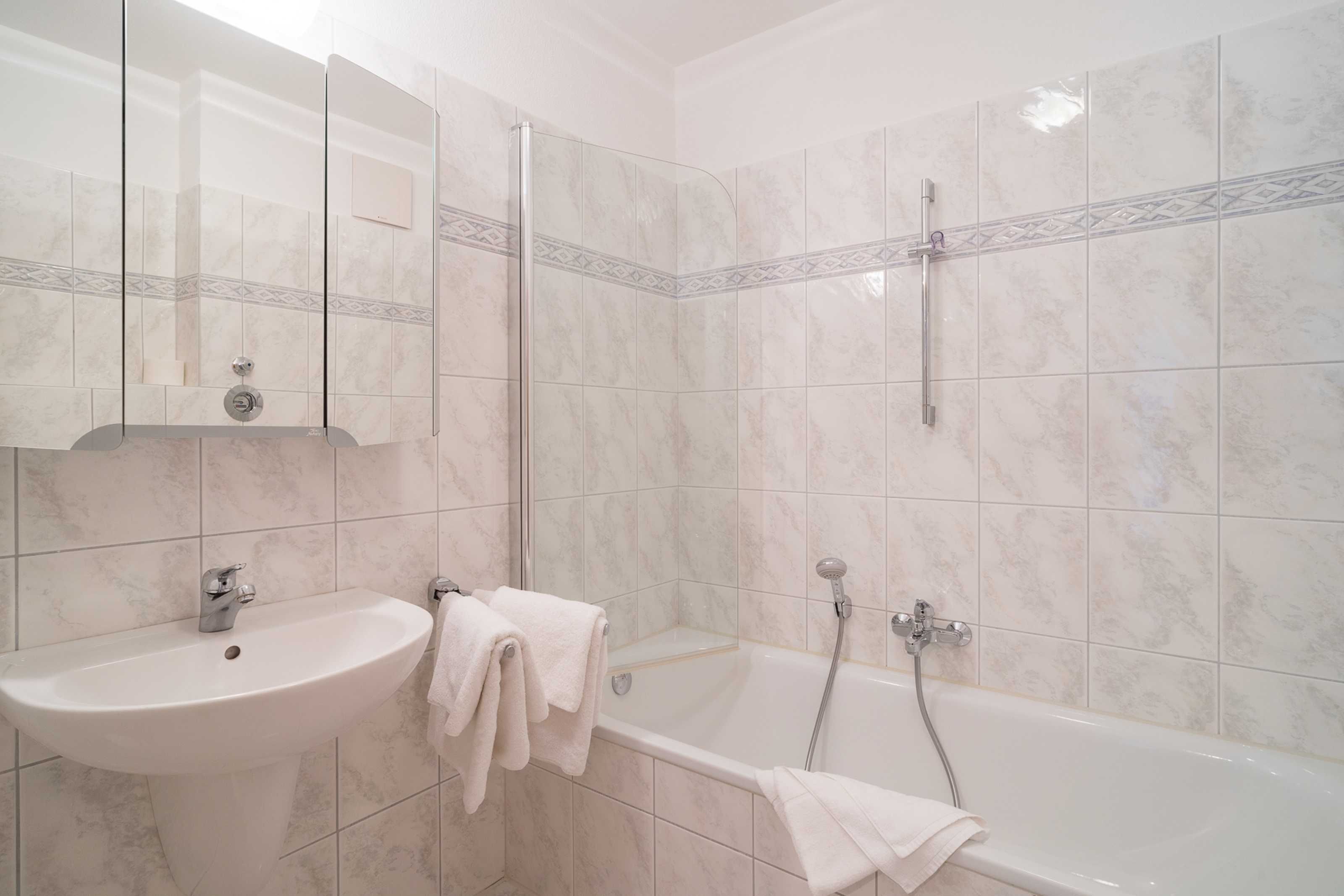 Ein Badezimmer mit Waschbecken, Spiegel und Duschbereich.