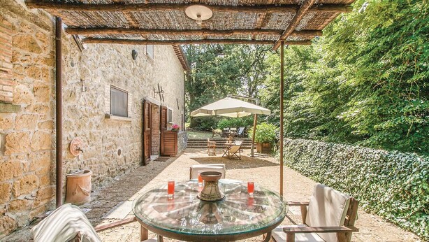 A rustic stone building with a glass table and wooden chairs under a thatched roof. - 3 bedroom awesome home in Montefiascone (VT) (Montefiascone (VT))