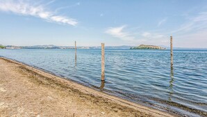 A calm lake with wooden posts in the water, a sandy beach, and distant hills. - 3 bedroom awesome home in Montefiascone (VT) (Montefiascone (VT))