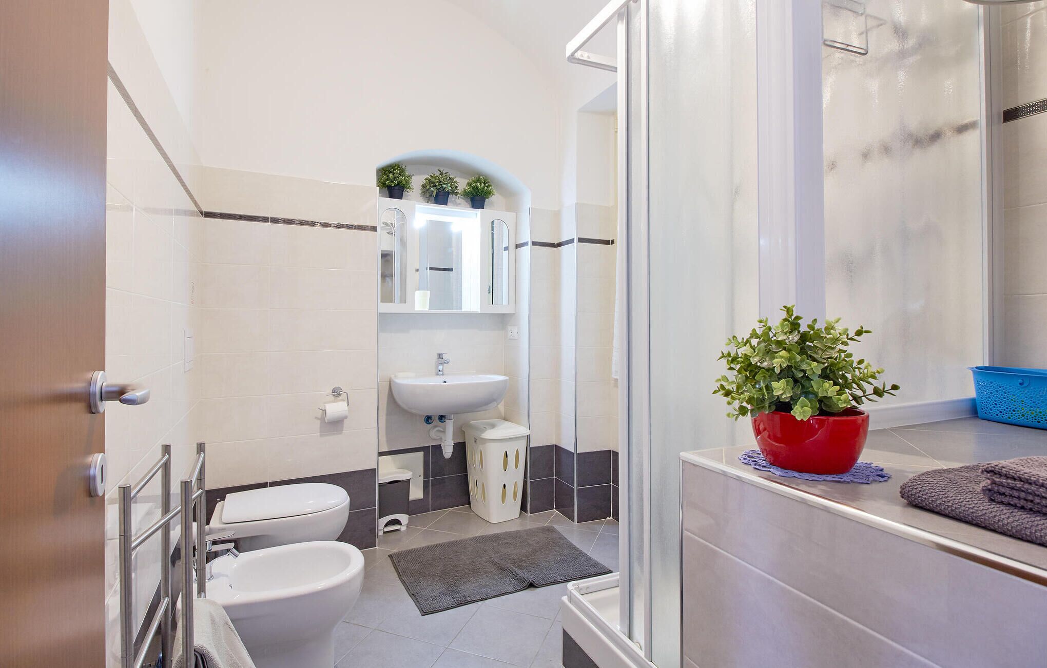Une salle de bain moderne avec deux toilettes, un lavabo, un miroir et une douche.