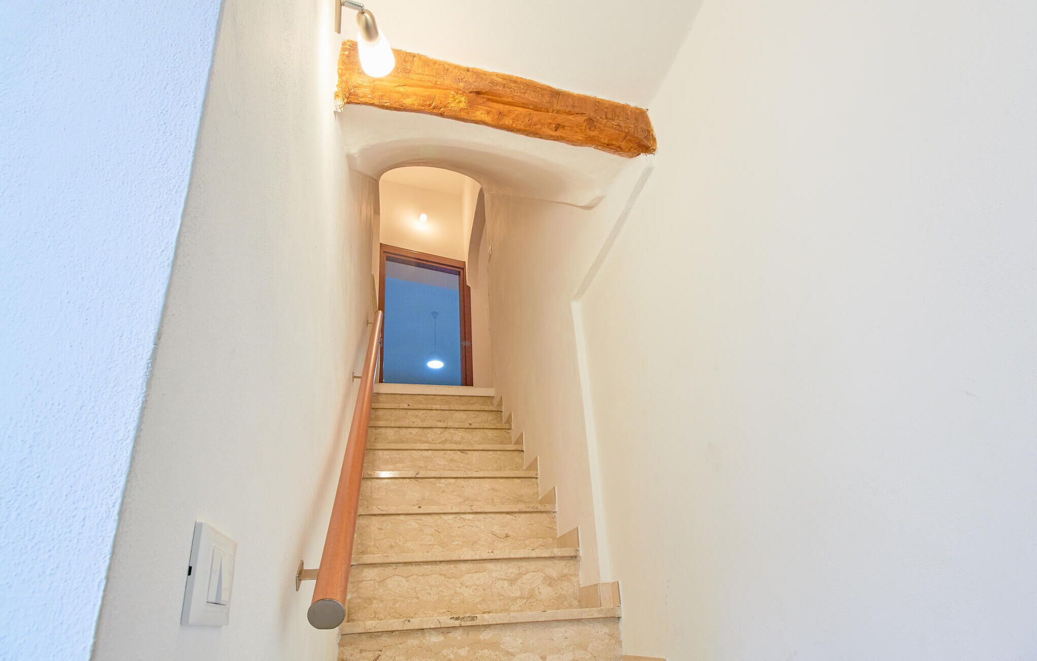 A staircase with a wooden handrail and a light fixture above it.
