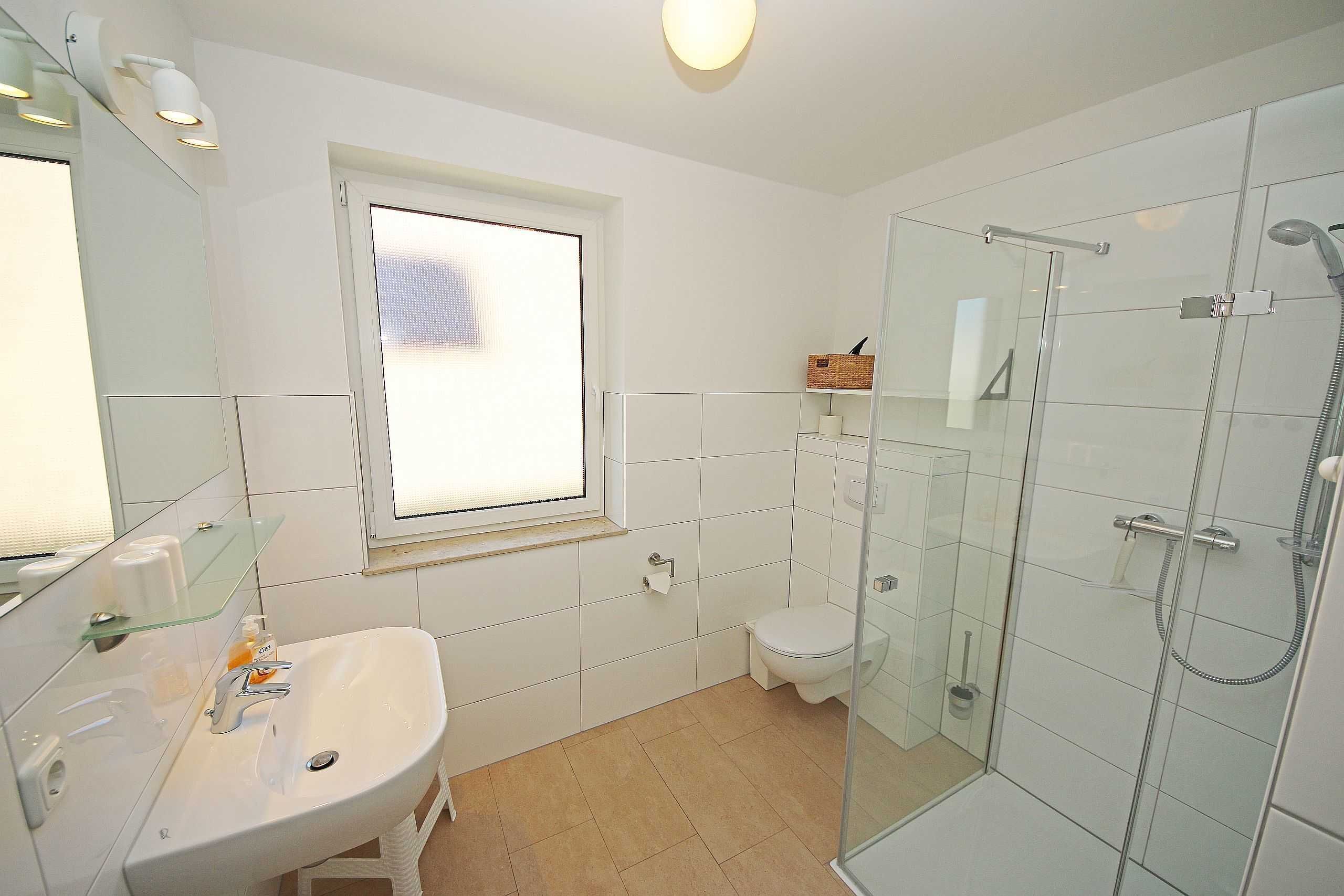 Une salle de bain avec une douche à parois de verre, un lavabo blanc et des toilettes.