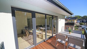 A modern house with a wooden deck, large sliding glass doors leading to an outdoor dining area with a table and chairs. - Vacation home Igelbau Whg. 01 with terrace - MR: Holiday home Igelbau with 2 (Baabe)