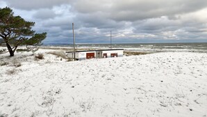 A snowy landscape with a building featuring a red door and a small structure. - Vacation home Igelbau Whg. 01 with terrace - MR: Holiday home Igelbau with 2 (Baabe)