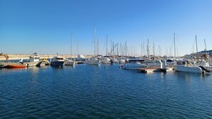 Ein Yachthafen mit verschiedenen Schiffen, ruhigem Wasser und blauem Himmel.