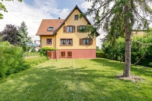 A two-story house with a sloped roof, multiple windows, and a well-maintained lawn. - Homerez - Apartment in Epfig (Epfig)