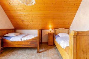A room with two wooden beds, a nightstand with a lamp, and a wooden ceiling. - Homerez - Apartment in Epfig (Epfig)