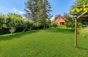 A well-maintained lawn with a wooden pergola and a house with a gabled roof in the background. - Homerez - Apartment in Epfig (Epfig)