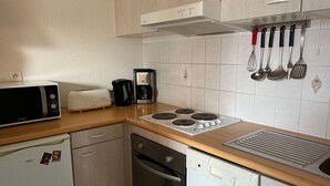 Une cuisine compacte équipée d’un four à micro-ondes, d’un grille-pain, d’une machine à café et d’une cuisinière. Elle comprend également des placards, un lave-vaisselle et un évier.