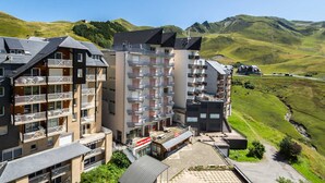 Un hôtel à plusieurs étages, doté de balcons, d’une cour intérieure et offrant une vue sur des collines verdoyantes.