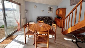 Un comedor con una mesa redonda de madera y sillas, un sofá, un armario y una escalera.