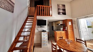 Una cocina amplia con armarios de madera, un comedor con mesa redonda y una escalera que sube a un nivel superior.