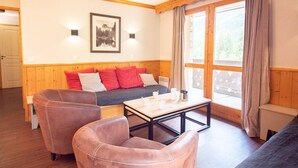 A cozy room with a wooden bench, a sofa with red cushions, a coffee table, and a framed picture on the wall. - Large 5-bedroom apartment Valmorel, pets allowed, parking (Valmorel)