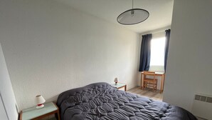 A bedroom with a large bed, a desk, a chair, and a window with curtains. - Cozy apartment with balcony, slope access, 6 people, Peyresourde (Peyragudes)
