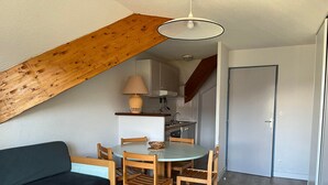 A compact living space with a dining area, kitchenette, and a lofted sleeping area. - Cozy apartment with balcony, slope access, 6 people, Peyresourde (Peyragudes)