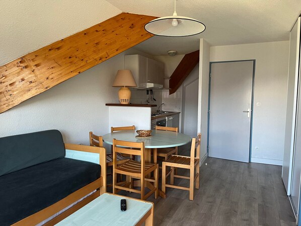 A compact living space with a dining area, kitchenette, and a lofted sleeping area.