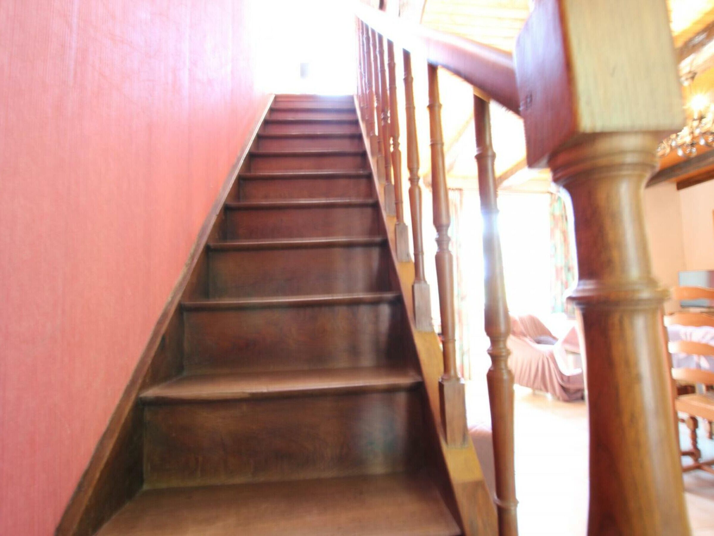 A wooden staircase with a handrail, leading upwards.