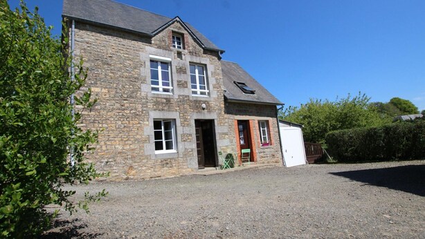 Une maison en pierre avec un garage, une porte d’entrée et un petit porche.
