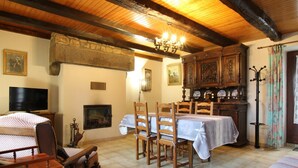 Une pièce chaleureuse avec un plafond en bois, une cheminée, une table à manger avec des chaises, un téléviseur et un lit.