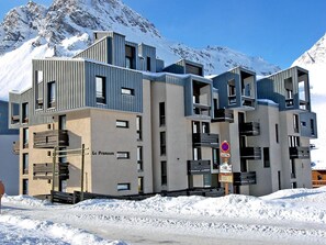 A multi-story hotel with balconies and a snow-covered mountain backdrop. - Charming studio in Tignes - 4 ppl, pets allowed (Tignes)