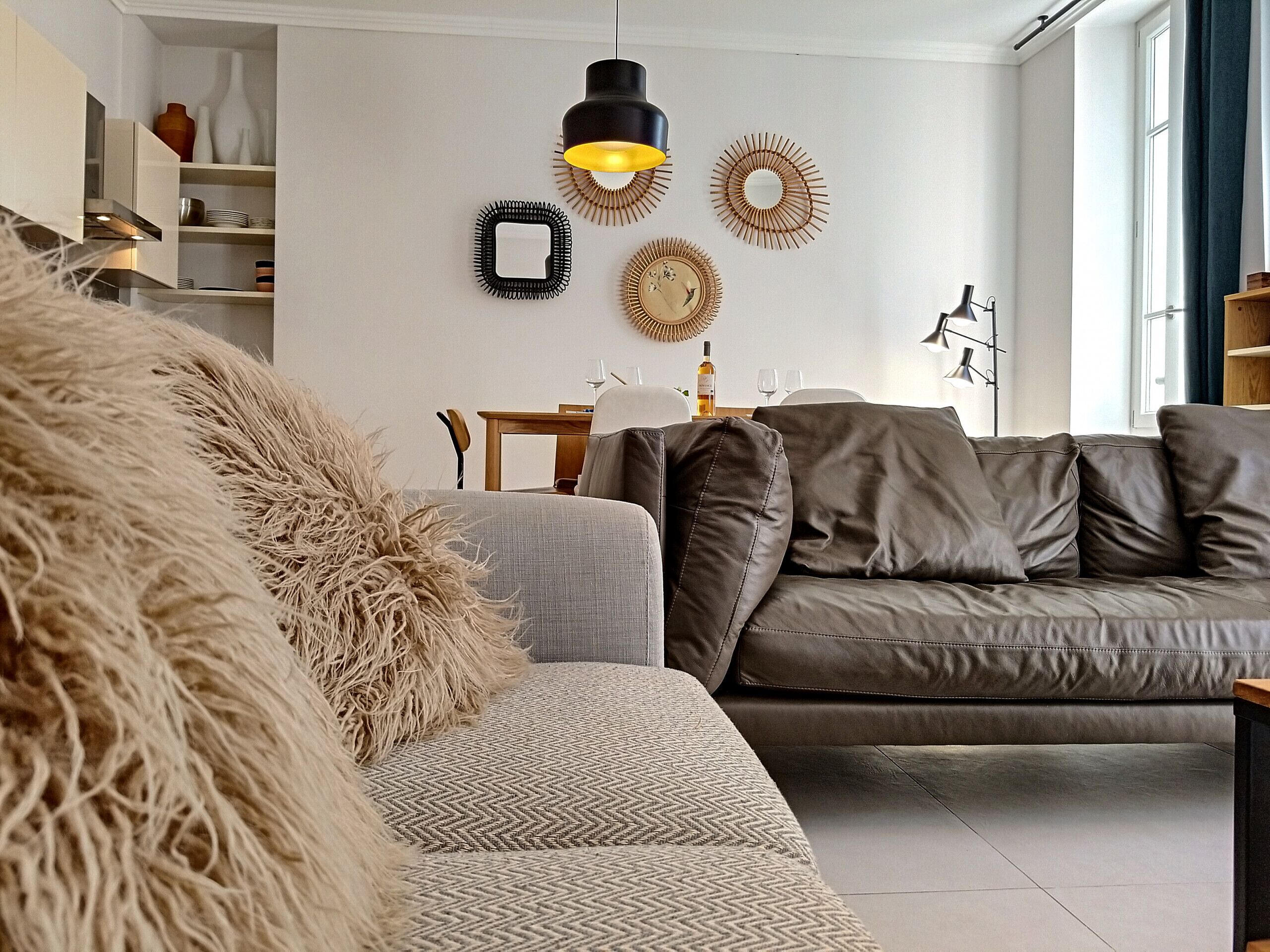 A modern living room with a grey sofa, a patterned armchair, and a fluffy throw.
