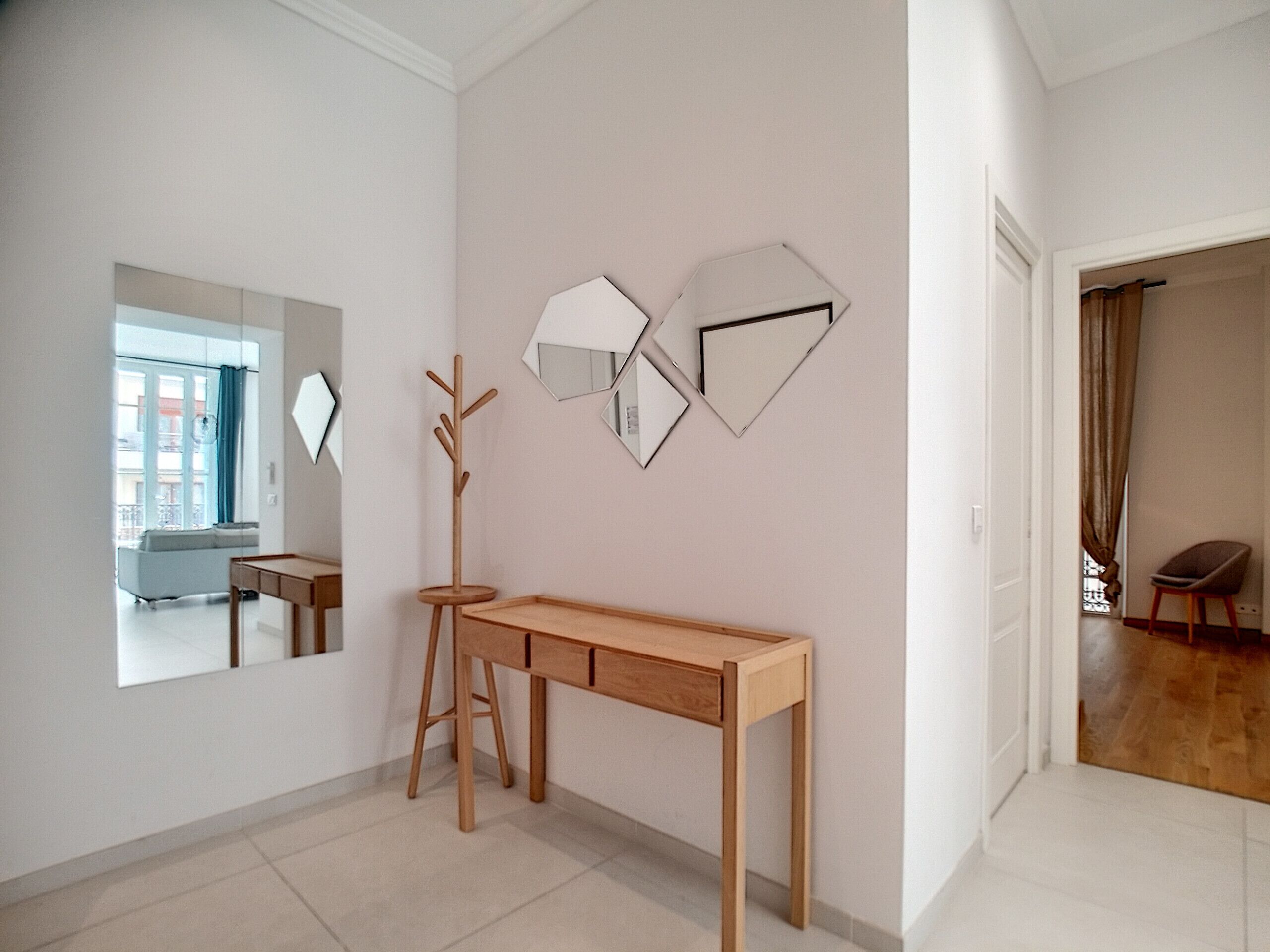 Habitació moderna i minimalista amb escriptori de fusta, penjador i un mirall gran.