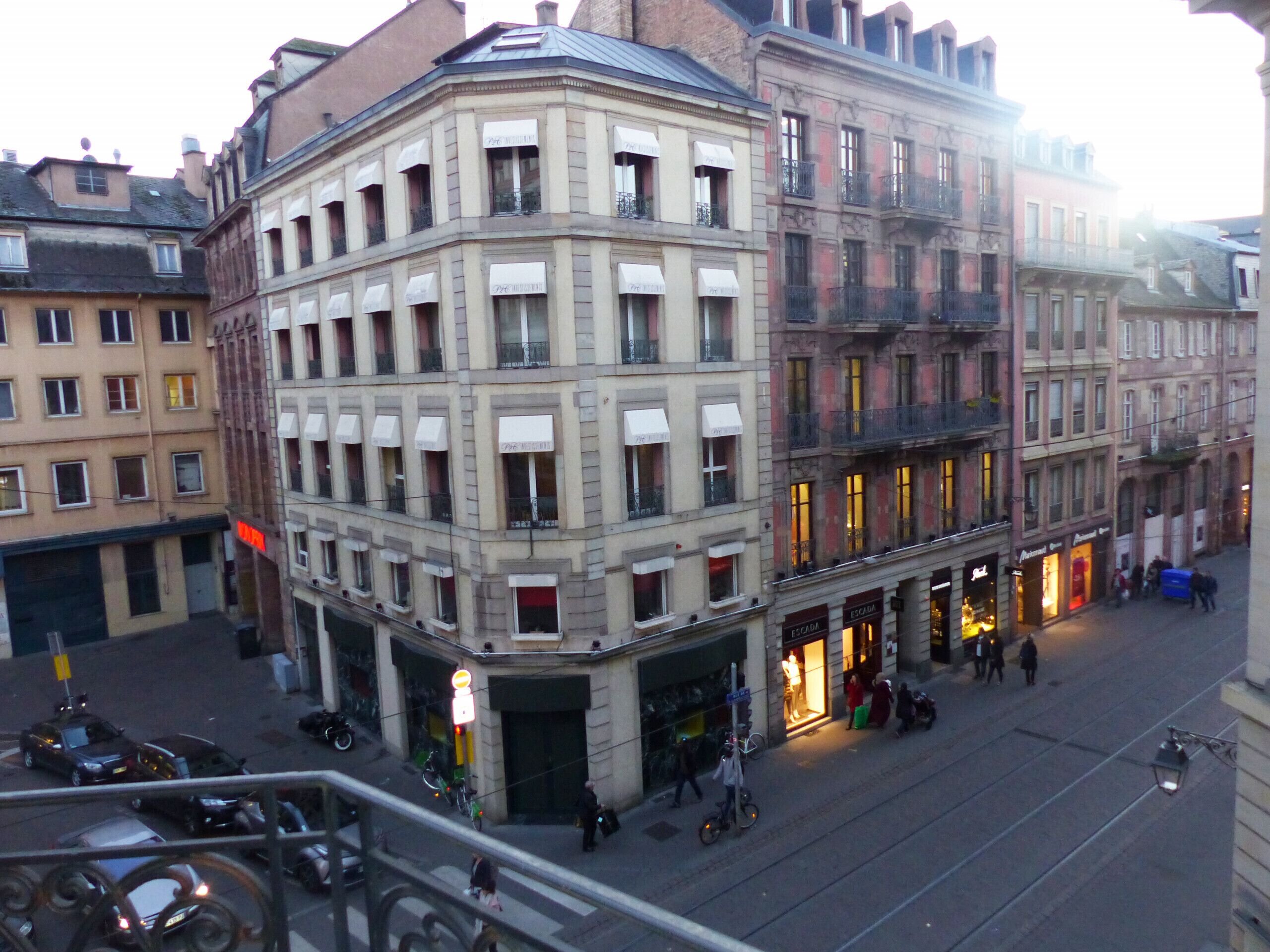 A multi-story building with a corner entrance, large windows, and a ground-floor shop with illuminated signage.