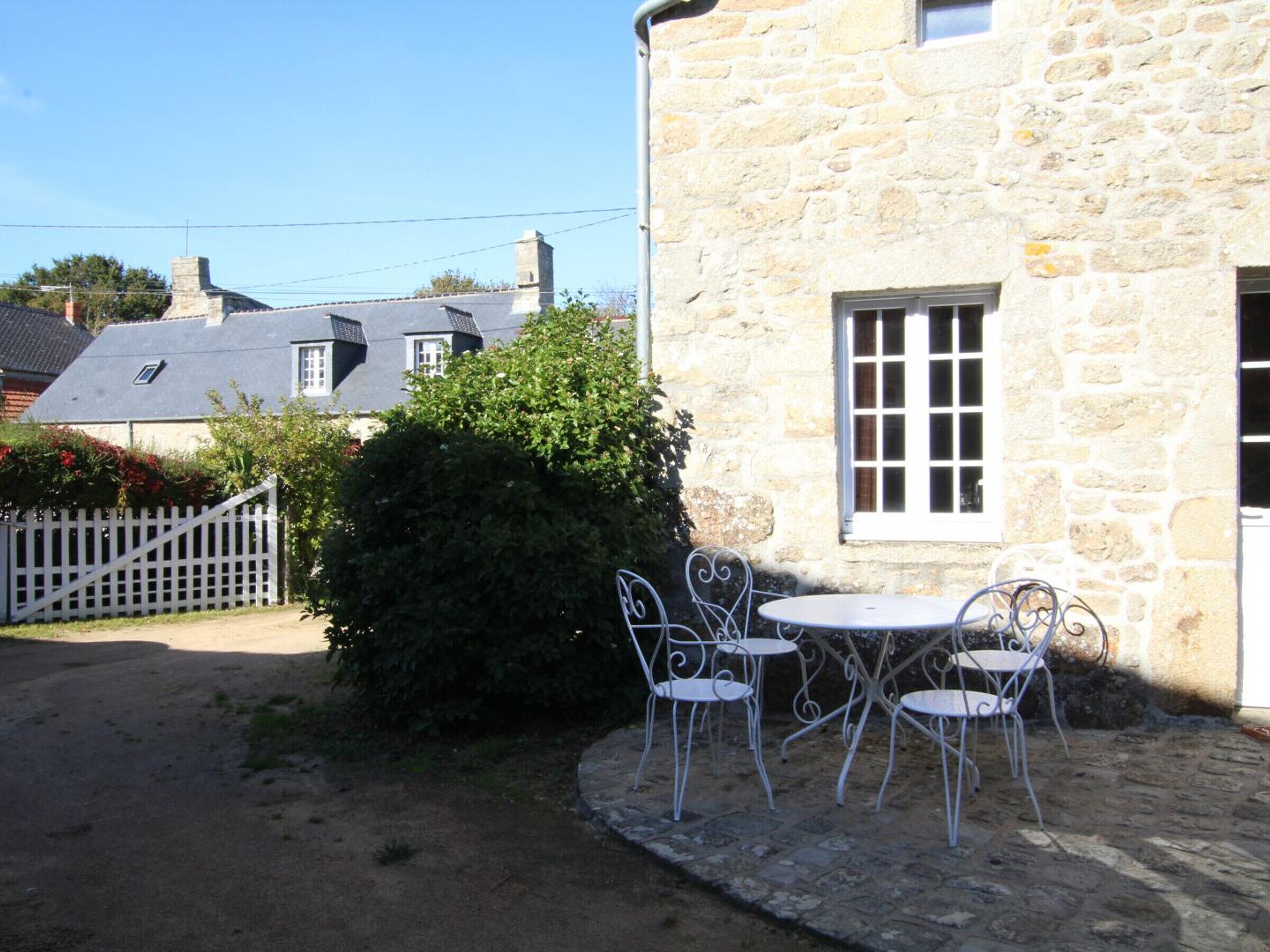 A stone building with a small patio area featuring metal chairs and a table.