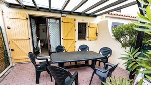 A patio with a table and chairs, a yellow gate, and a potted plant. - Homerez - House in Argelès-sur-Mer with shared pool (Argelès-sur-Mer)